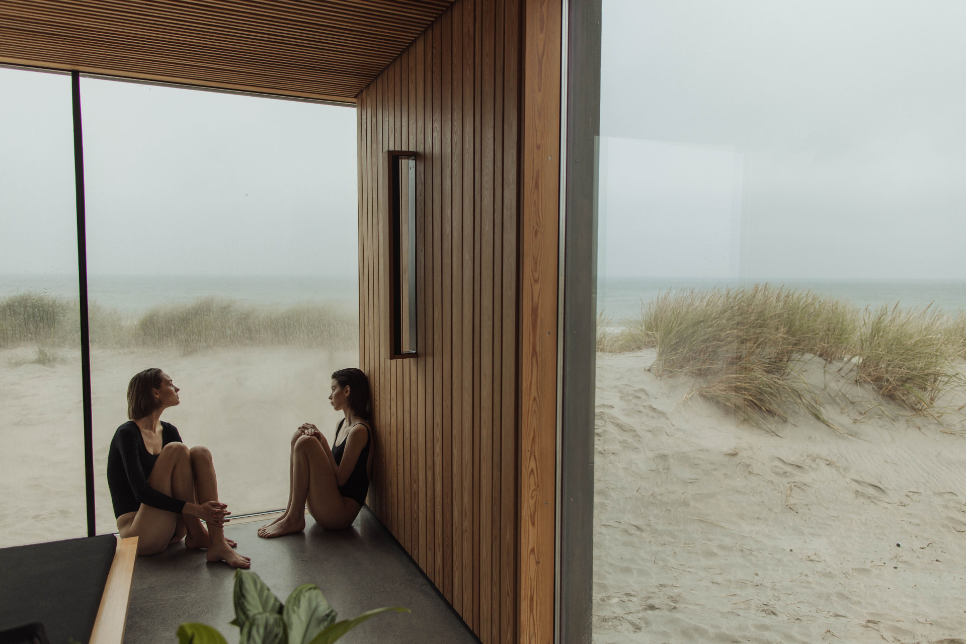 Two practitioners sitting and talking in a wooden studio by the dunes
