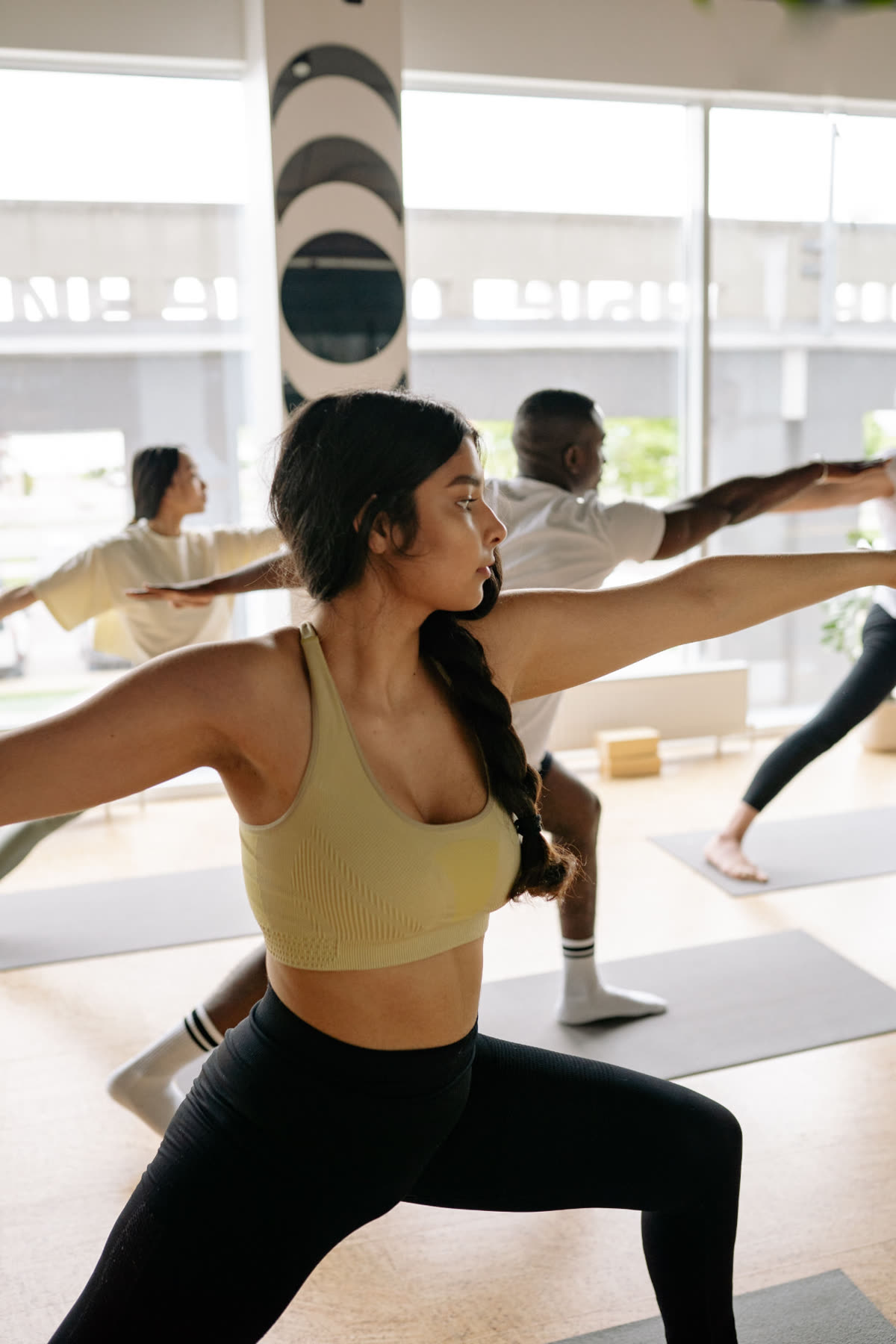 Practitioners moving through a class together in a light-filled studio